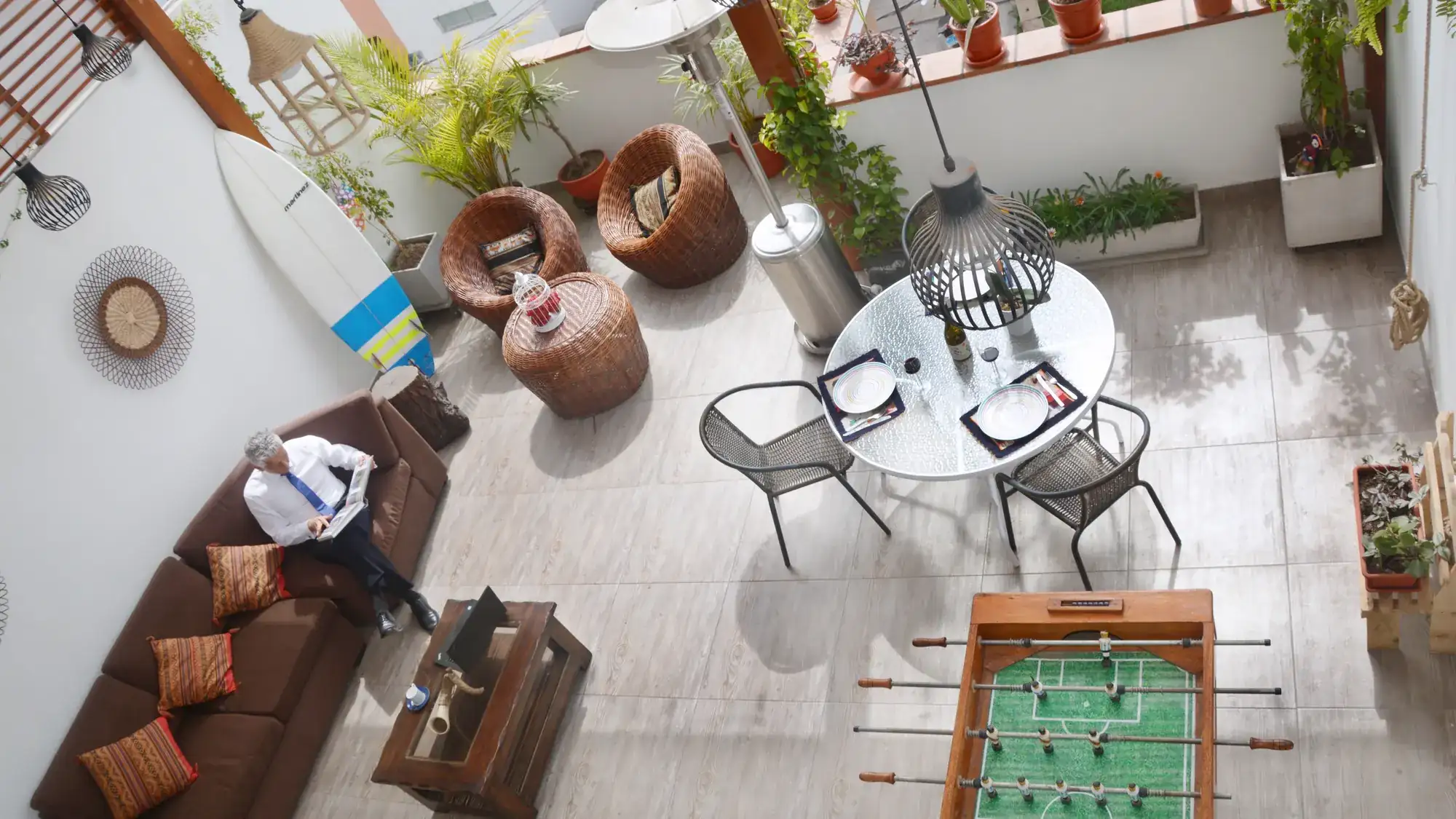 La terraza compartida vista desde arriba, con sofás de mimbre, mesa, futbolín y plantas