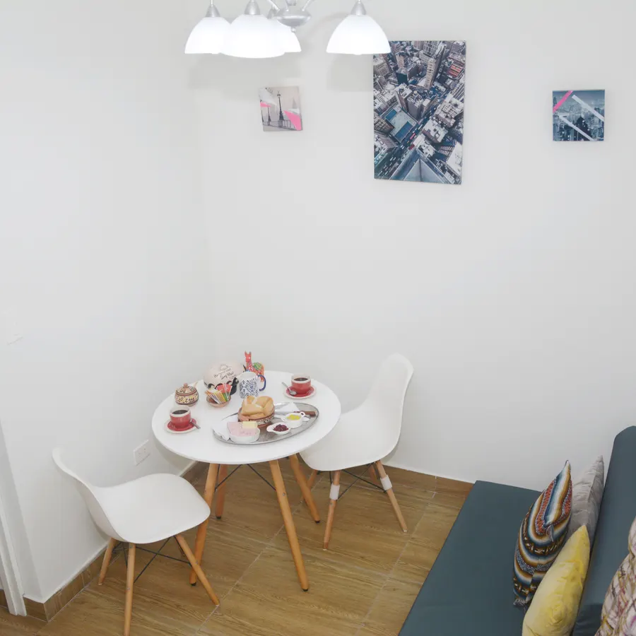 Comedor del piso 1, con mesa redonda, sillas blancas y banco tapizado