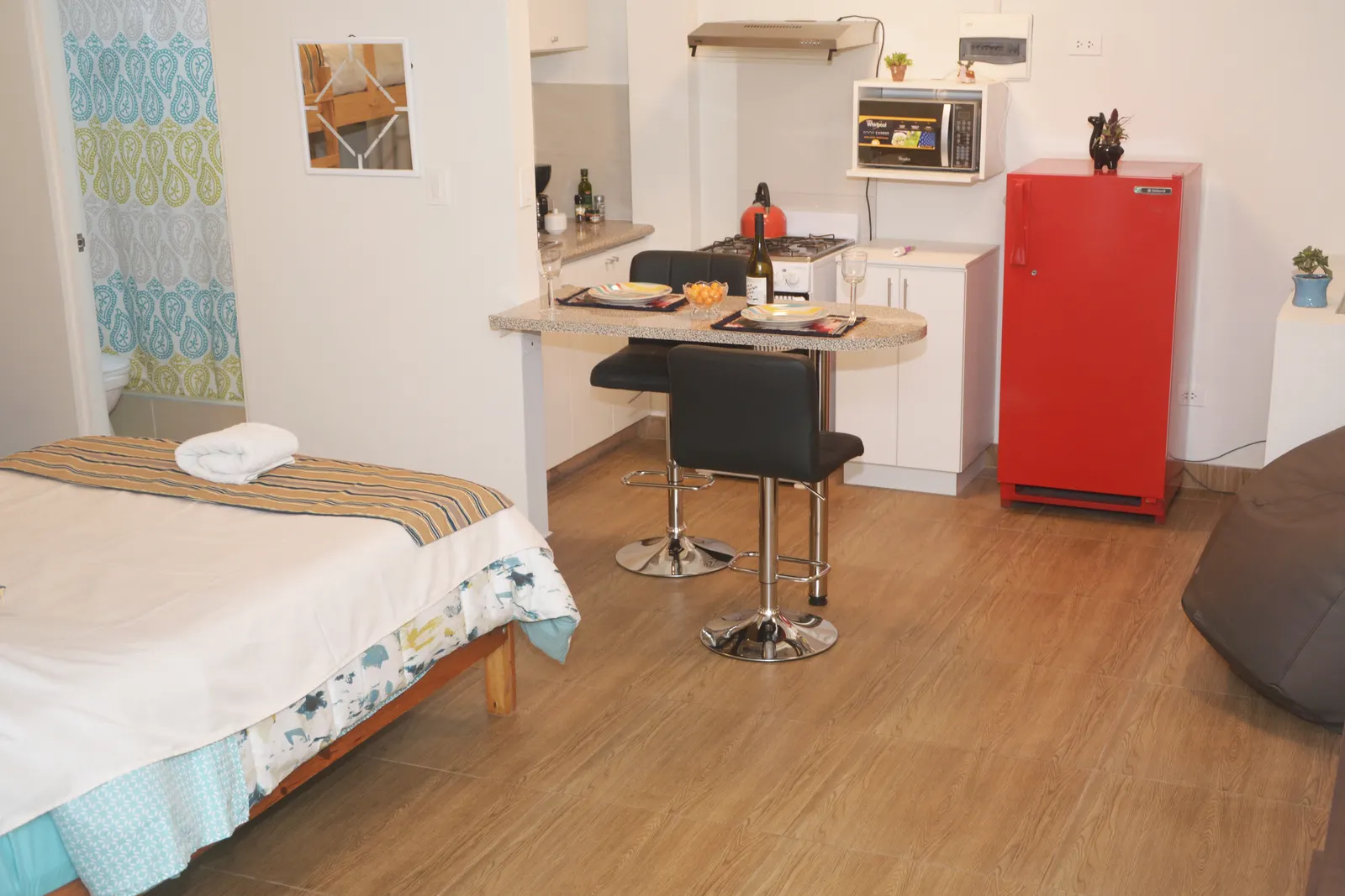 Cama doble del apartamento del piso 2, con la cocina y la refrigeradora roja al fondo