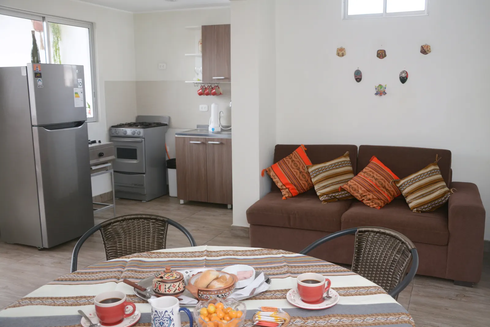 Comedor del apartamento del piso 4 con el desayuno servido, la cocina y el sofá al fondo